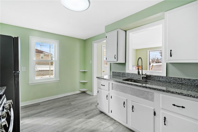 kitchen with white cabinetry, sink, dark stone countertops, stove, and black fridge