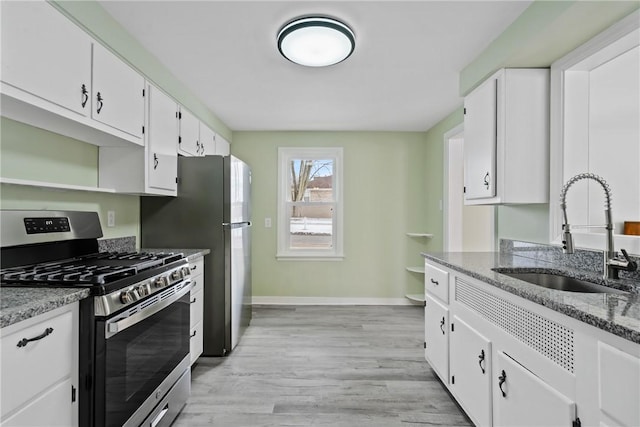 kitchen with white cabinetry, stainless steel appliances, light stone countertops, and sink