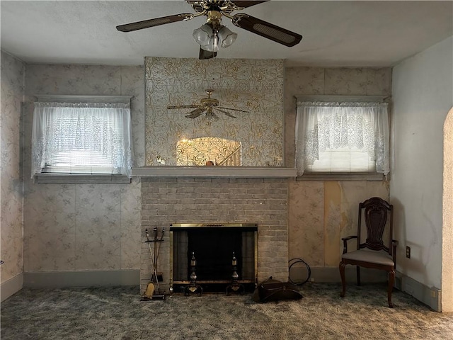 unfurnished living room featuring ceiling fan, carpet flooring, and a brick fireplace