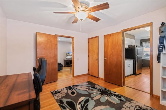 bedroom featuring stainless steel refrigerator, ceiling fan, multiple closets, and light hardwood / wood-style flooring