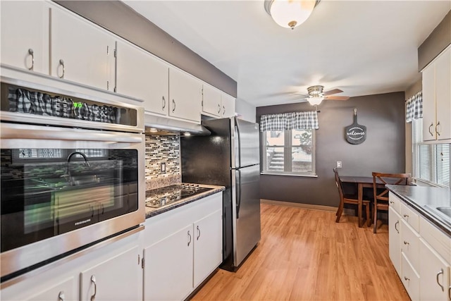 kitchen with white cabinetry, light hardwood / wood-style flooring, ceiling fan, stainless steel appliances, and decorative backsplash