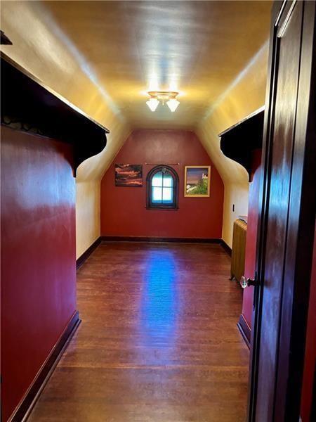 bonus room with dark hardwood / wood-style floors and vaulted ceiling