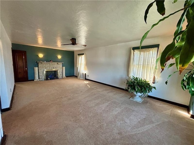 unfurnished living room featuring ceiling fan, light colored carpet, a textured ceiling, and a fireplace