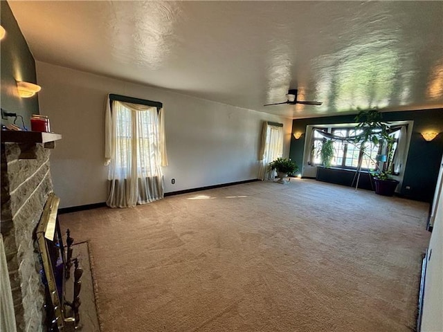 unfurnished living room with ceiling fan, a fireplace, and carpet