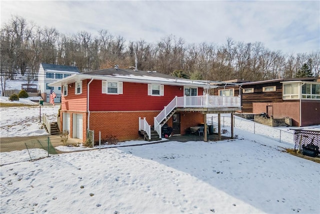 snow covered rear of property featuring a garage and a deck