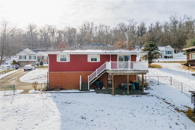 snow covered back of property featuring a deck