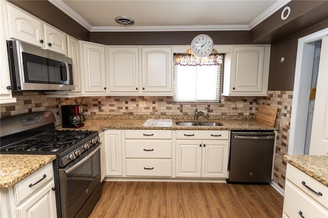 kitchen with appliances with stainless steel finishes, light stone countertops, sink, and white cabinets