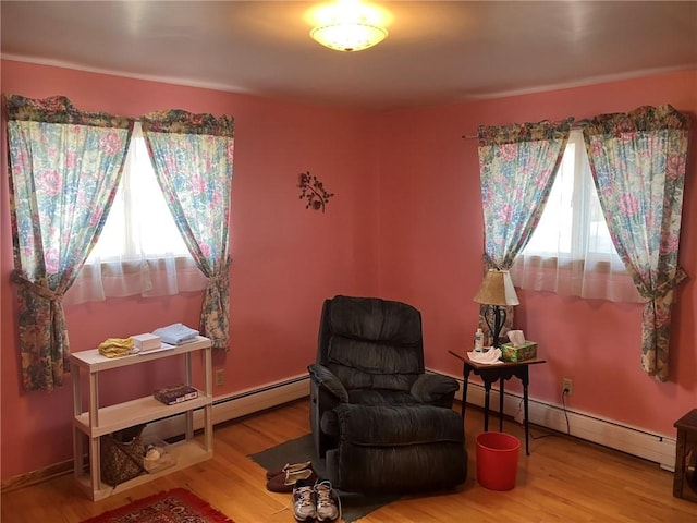 sitting room featuring a baseboard heating unit and hardwood / wood-style floors