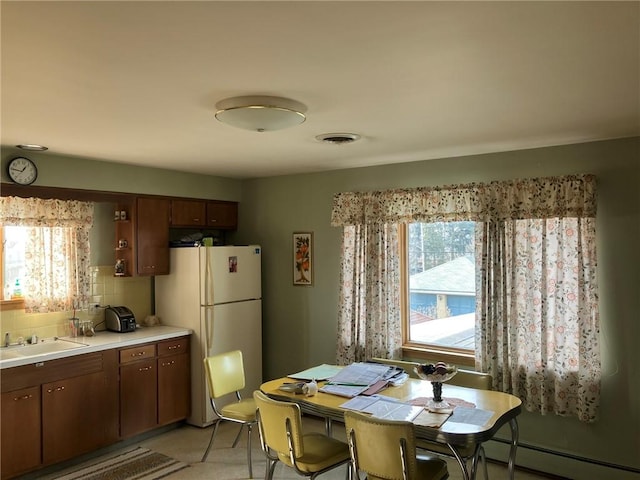 dining space featuring sink, plenty of natural light, and baseboard heating