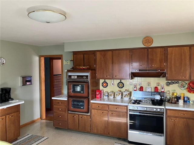 kitchen featuring multiple ovens, white gas range, and backsplash