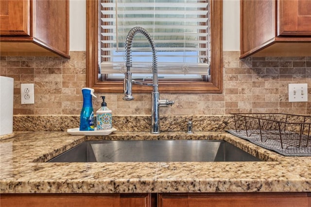 kitchen featuring light stone countertops, sink, and backsplash