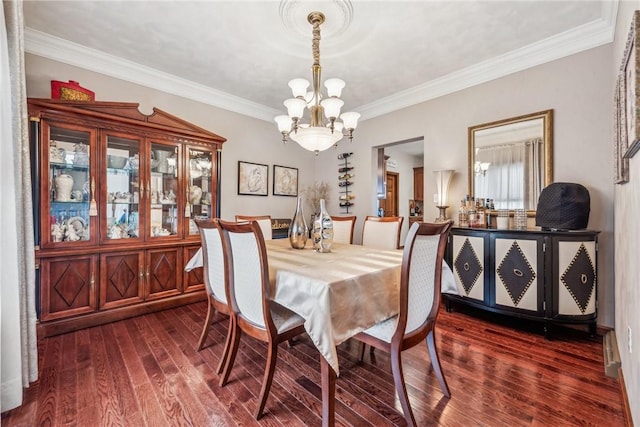 dining room with ornamental molding, dark hardwood / wood-style floors, and a notable chandelier