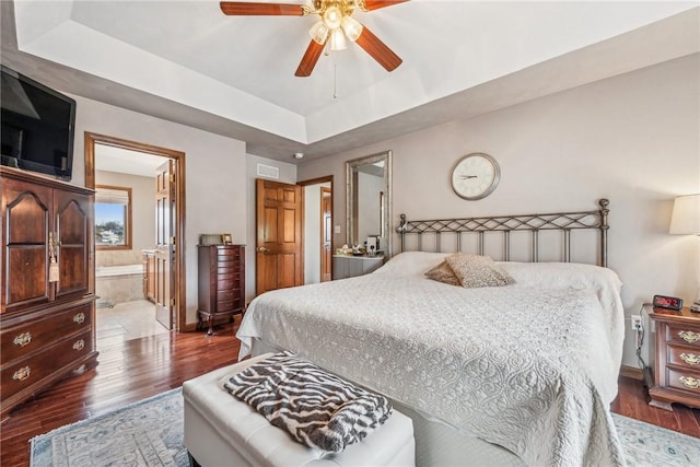 bedroom featuring a raised ceiling, wood-type flooring, connected bathroom, and ceiling fan