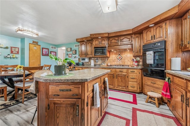 kitchen with premium range hood, backsplash, black microwave, a center island, and gas stovetop