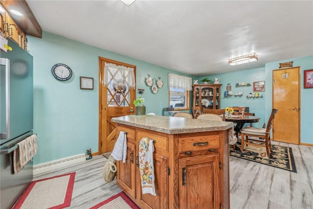 kitchen featuring a baseboard radiator, stainless steel fridge, a kitchen island, and light wood-type flooring