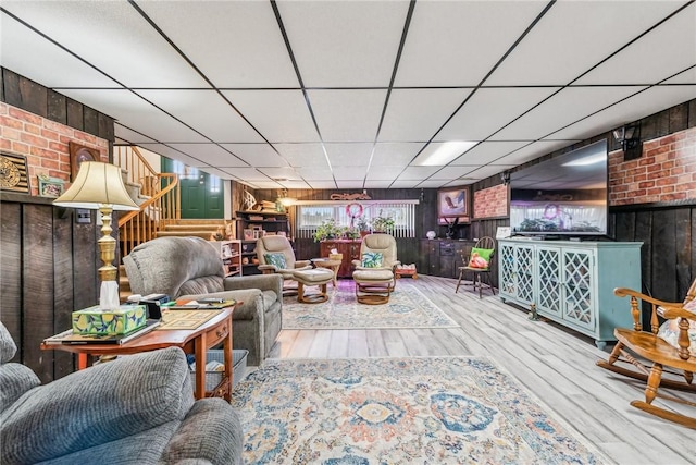 living room with hardwood / wood-style floors, bar, a paneled ceiling, and wooden walls