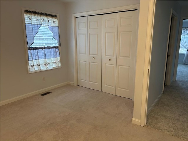 unfurnished bedroom with multiple windows, a closet, and light carpet