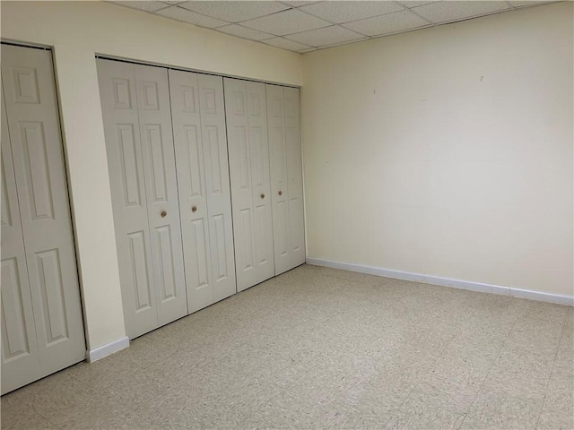 unfurnished bedroom featuring a drop ceiling and a closet