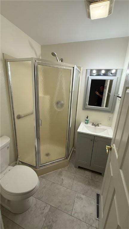 bathroom featuring vanity, a shower with shower door, and toilet