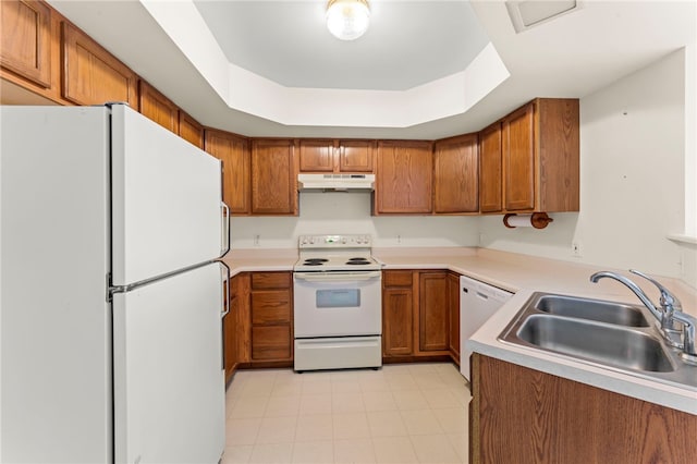 kitchen with white appliances, a tray ceiling, and sink