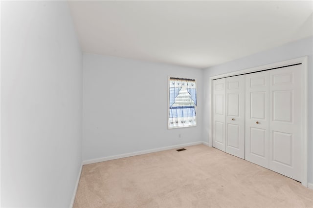 unfurnished bedroom featuring light colored carpet and a closet