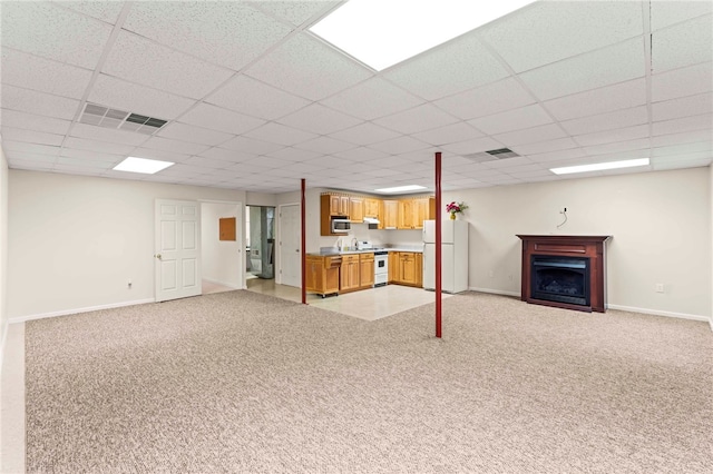 basement featuring light carpet, white fridge, and a drop ceiling