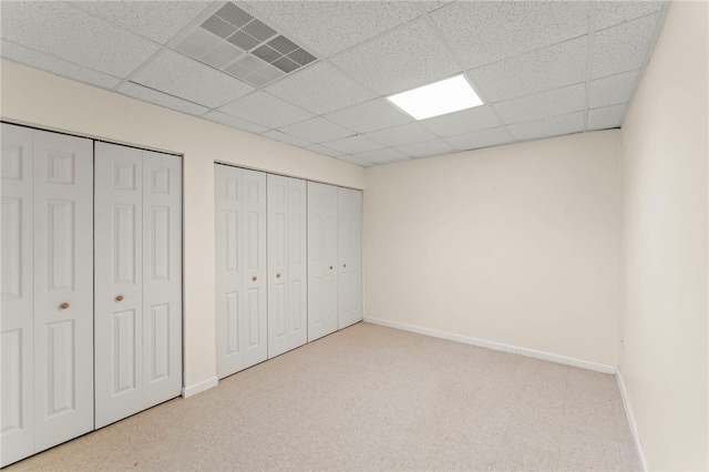 unfurnished bedroom with a drop ceiling and two closets