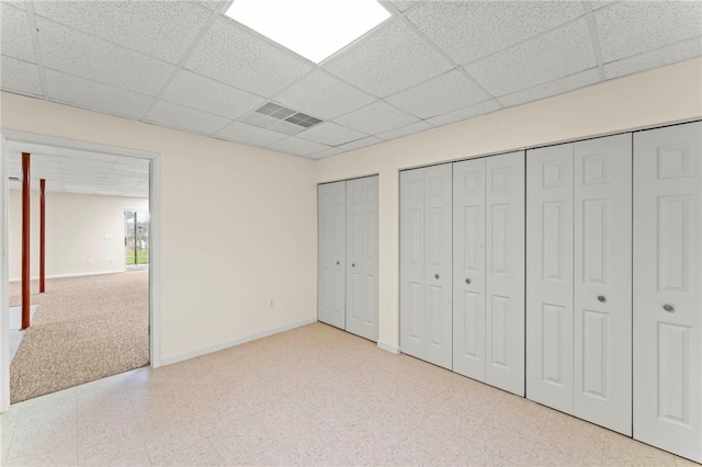 unfurnished bedroom with two closets and a paneled ceiling