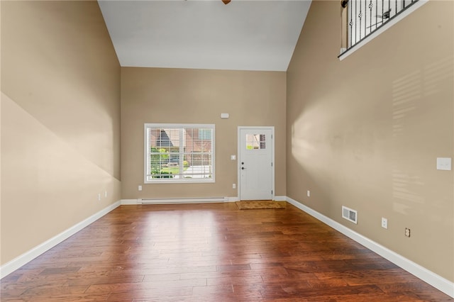 entryway featuring a baseboard heating unit, dark hardwood / wood-style floors, and a high ceiling