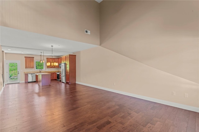 unfurnished living room with a high ceiling, sink, and dark hardwood / wood-style flooring