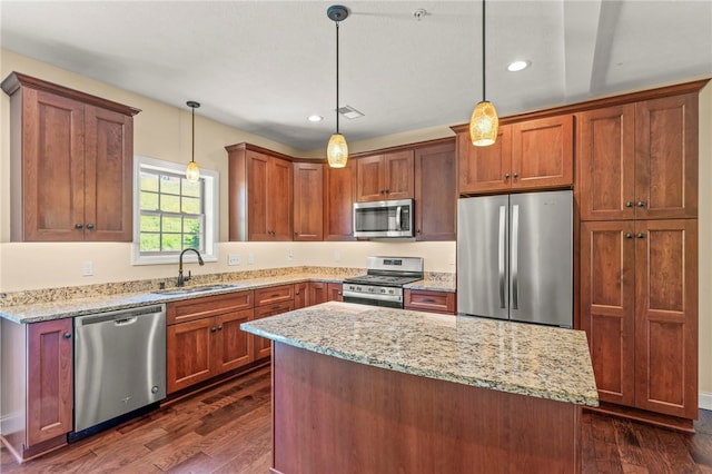 kitchen featuring appliances with stainless steel finishes, dark hardwood / wood-style floors, sink, hanging light fixtures, and a center island