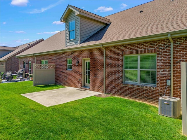 rear view of property with cooling unit, a patio area, and a lawn