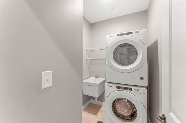 washroom with stacked washer / drying machine, light hardwood / wood-style floors, and sink