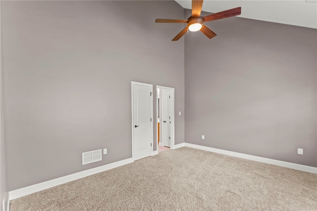 carpeted spare room featuring ceiling fan and a high ceiling