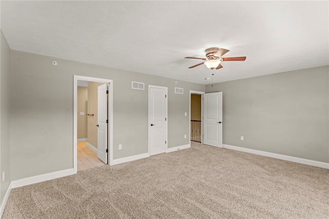 unfurnished bedroom featuring ceiling fan, ensuite bath, and light carpet