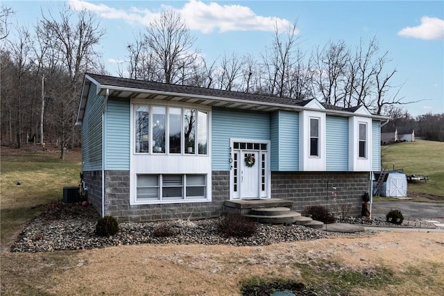 split foyer home featuring central AC and a front lawn