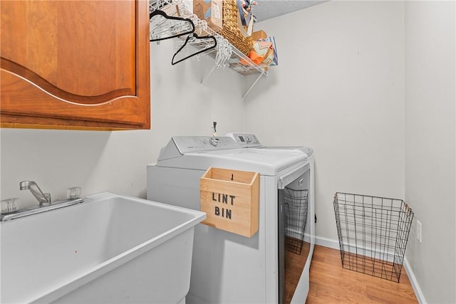 washroom featuring cabinets, separate washer and dryer, sink, and light wood-type flooring