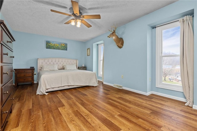 bedroom featuring hardwood / wood-style flooring, ceiling fan, and a textured ceiling