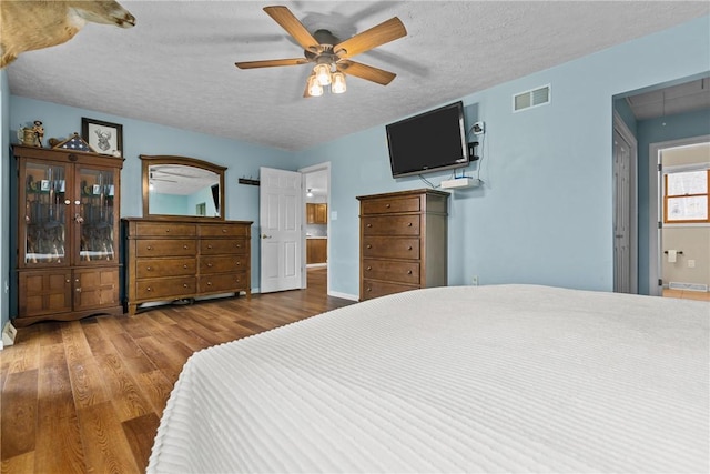 bedroom with hardwood / wood-style floors, a textured ceiling, and ceiling fan