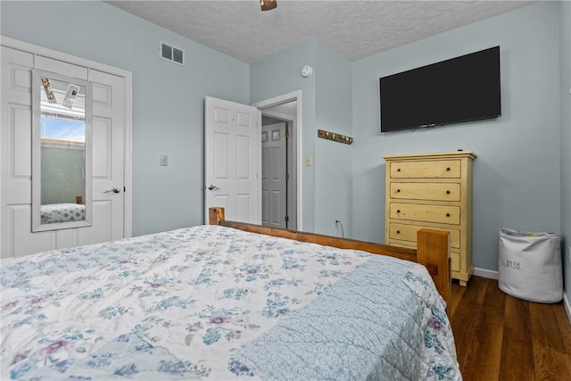 bedroom featuring dark wood-type flooring, ceiling fan, and a textured ceiling