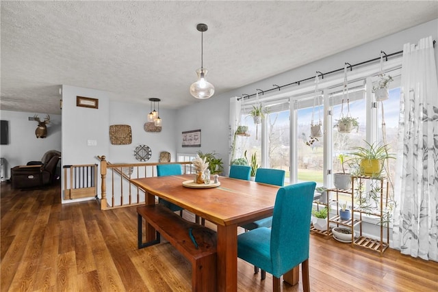 dining space with wood-type flooring and a textured ceiling