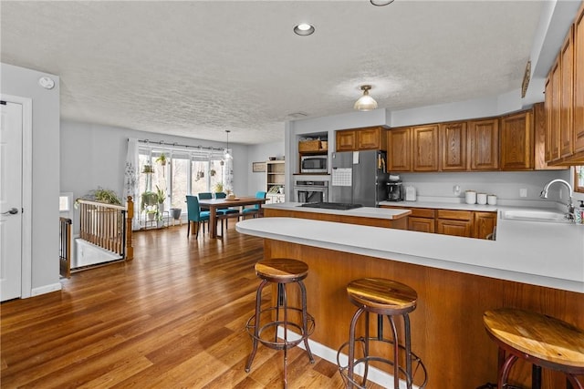 kitchen featuring a kitchen bar, sink, kitchen peninsula, pendant lighting, and stainless steel appliances