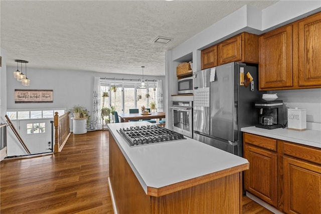 kitchen with pendant lighting, stainless steel appliances, dark hardwood / wood-style floors, and a center island