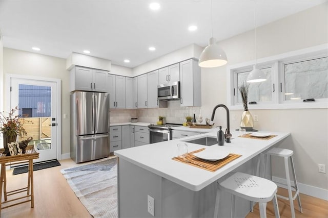 kitchen with pendant lighting, a breakfast bar area, kitchen peninsula, and appliances with stainless steel finishes