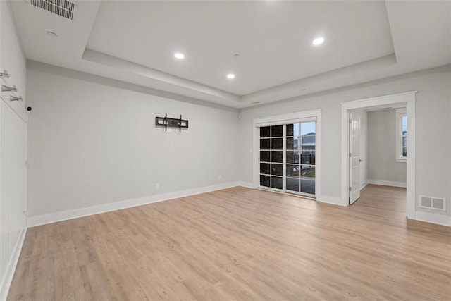 spare room with light hardwood / wood-style floors and a tray ceiling