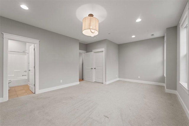 unfurnished bedroom featuring connected bathroom and light colored carpet