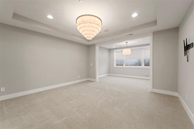 carpeted empty room with a tray ceiling