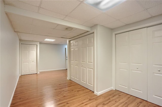 corridor featuring a paneled ceiling and light wood-type flooring