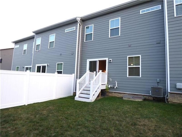 back of house with cooling unit and a yard