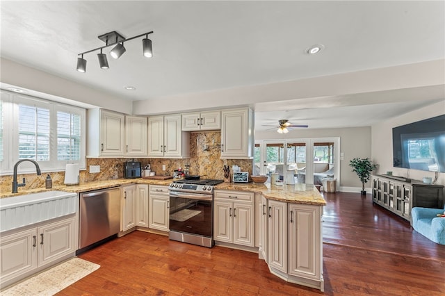 kitchen featuring appliances with stainless steel finishes, sink, decorative backsplash, light stone counters, and a healthy amount of sunlight